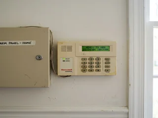 Older style alarm panel and keypad representing the simpler alarm systems common in Singapore before modern licensing standards